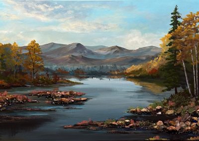 Fall landscape with aspen trees, calm water and soft mountains in the distance.