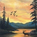 Acrylic sunrise landscape with an elk standing in glowing water, silhouetted trees, distant blue mountains, and birds crossing the sky; framed in a bronze metal floater frame.