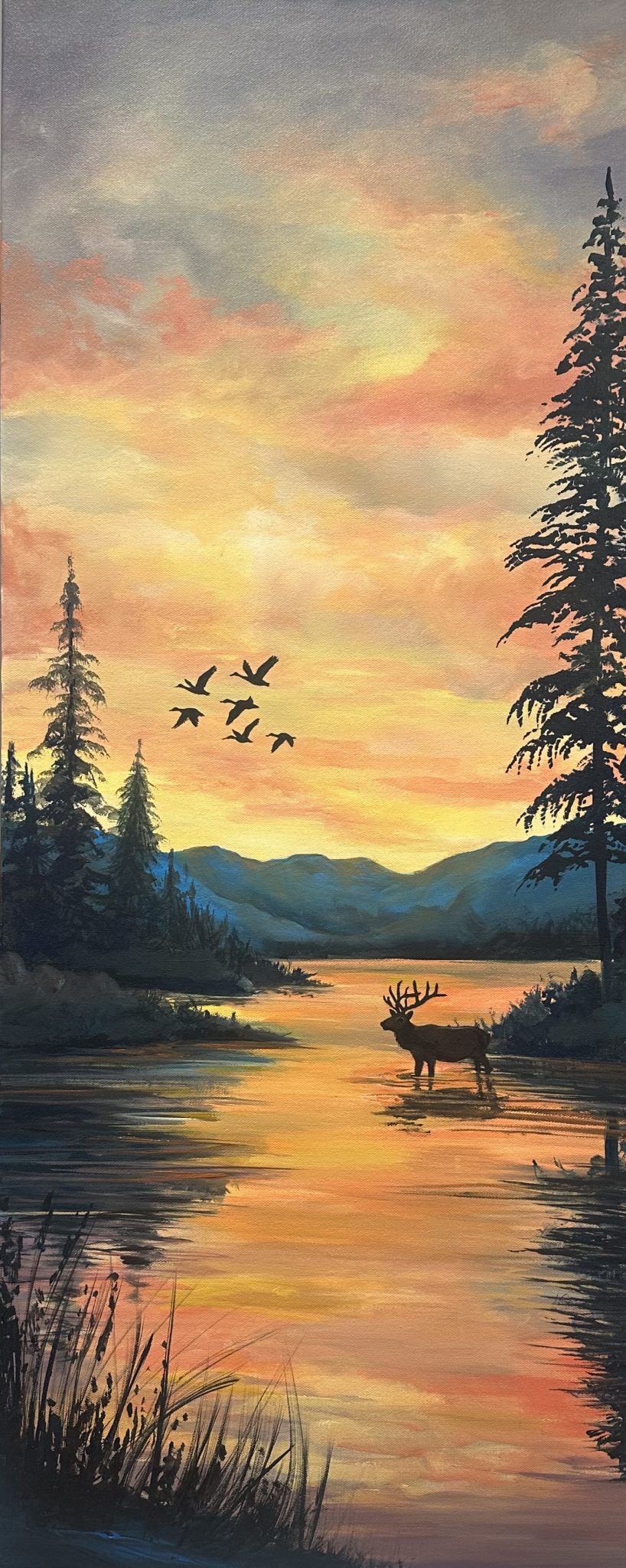 Acrylic sunrise landscape with an elk standing in glowing water, silhouetted trees, distant blue mountains, and birds crossing the sky; framed in a bronze metal floater frame.