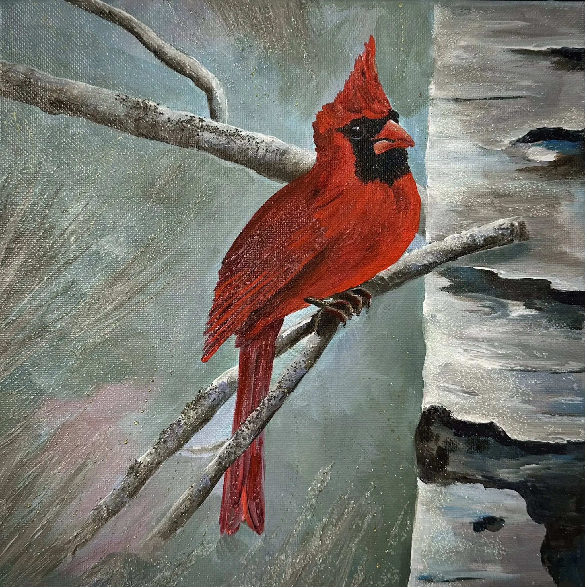 Branches of Tranquility A bright red cardinal sits on slender winter branches beside a textured birch trunk. Soft teal and gray tones form a snowy background with subtle sparkle from mica and glass glitter. The artwork is set in a silver floater frame.