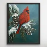 A vibrant red cardinal sits on a snow-covered pine branch in a teal winter sky. Mica and glass glitter add shimmering highlights to the feathers and snow. The artwork is framed in a sleek black floater frame.