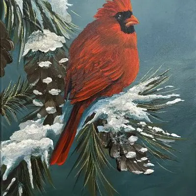 A vibrant red cardinal sits on a snow-covered pine branch in a teal winter sky. Mica and glass glitter add shimmering highlights to the feathers and snow. The artwork is framed in a sleek black floater frame.